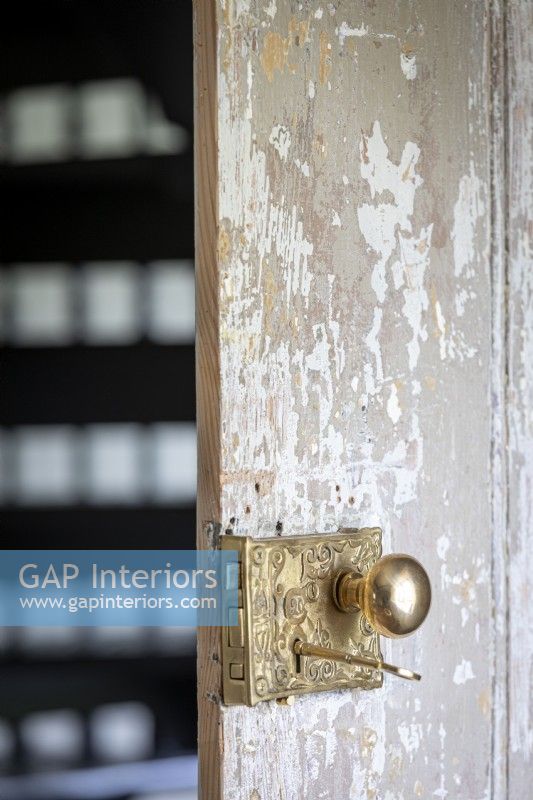 Rustic wooden door with ornate brass door handle in ancient stone cottage