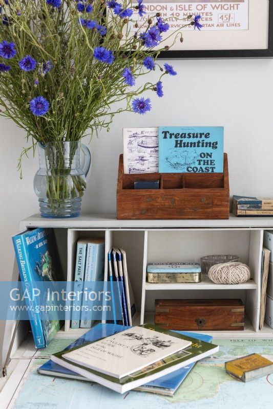 Vintage painted desk, with old guidebooks, map and a large vase of blue Knapweed flowers
