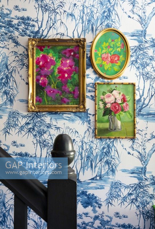 Framed floral paintings on wallpapered wall - hallway detail