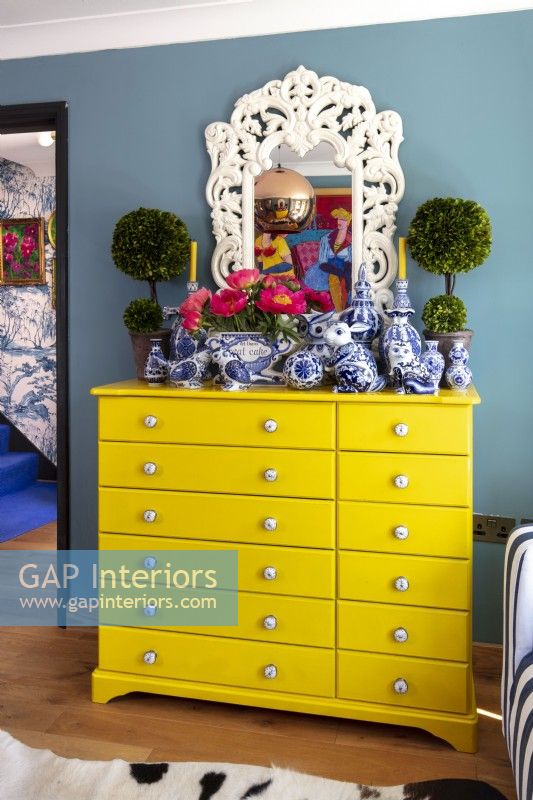 Bright yellow chest of drawers with display of ceramic ornaments