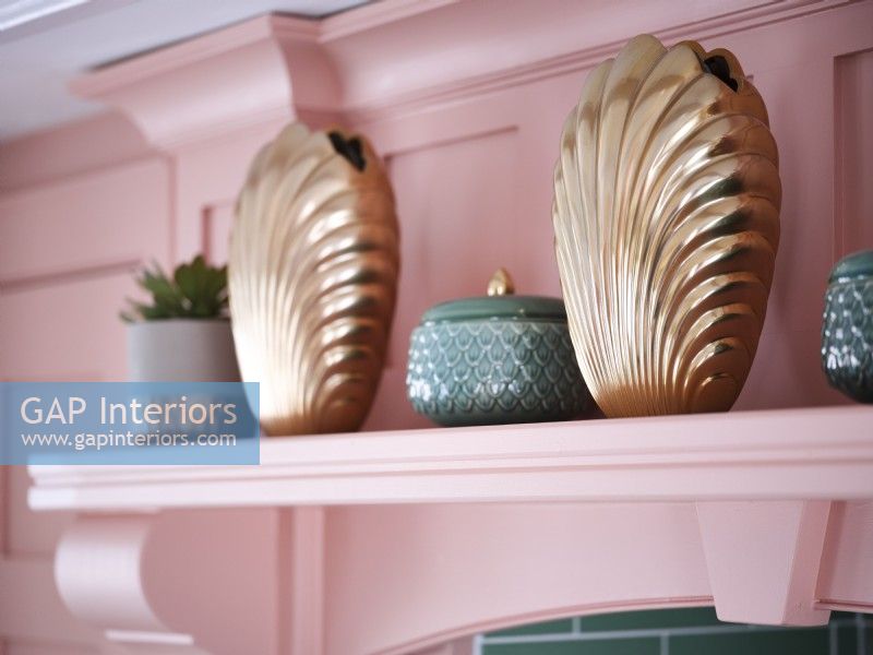 Gold clam shell ornaments on pink shelf