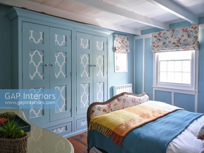 Light blue coastal themed bedroom with vintage upholstered bed