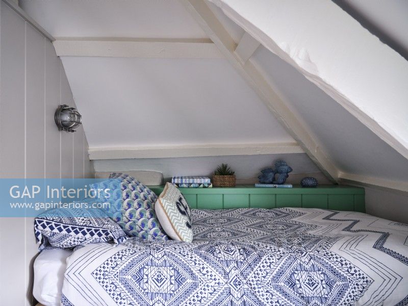 Blue and white bed furnishings in airy loft room 
