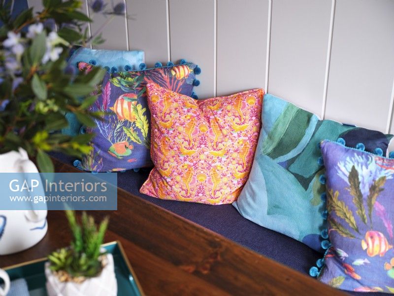 Colourful coastal themed cushions next to white panelled wall