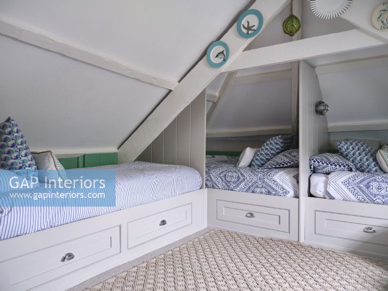 Airy loft room with blue and white coastal themed beds and built in storage