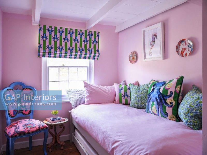 Pink bedroom with upholstered chair, coastal soft furnishings and artwork