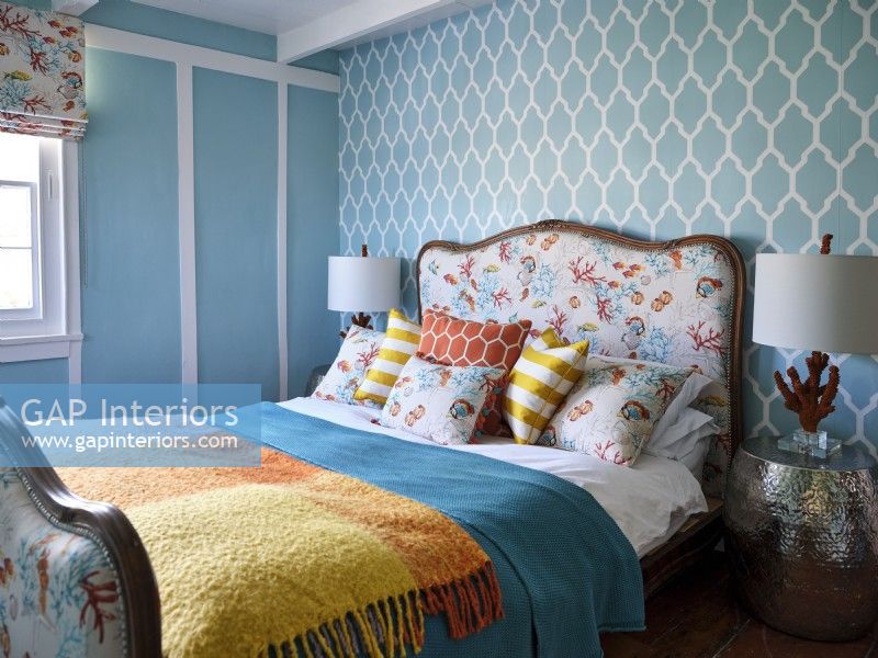Upholstered bed in front of blue and white patterned wall 