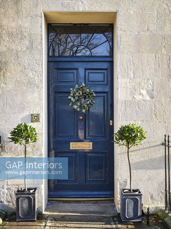 Black door with Christmas wreath and symmetrical plants