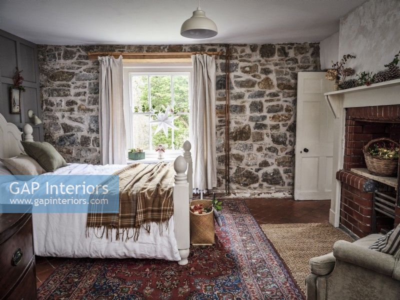 Country bedroom featuring stone wall and rustic rug