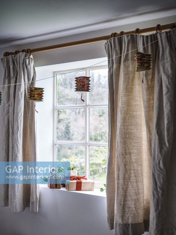 Window with hanging decorations and beige curtains