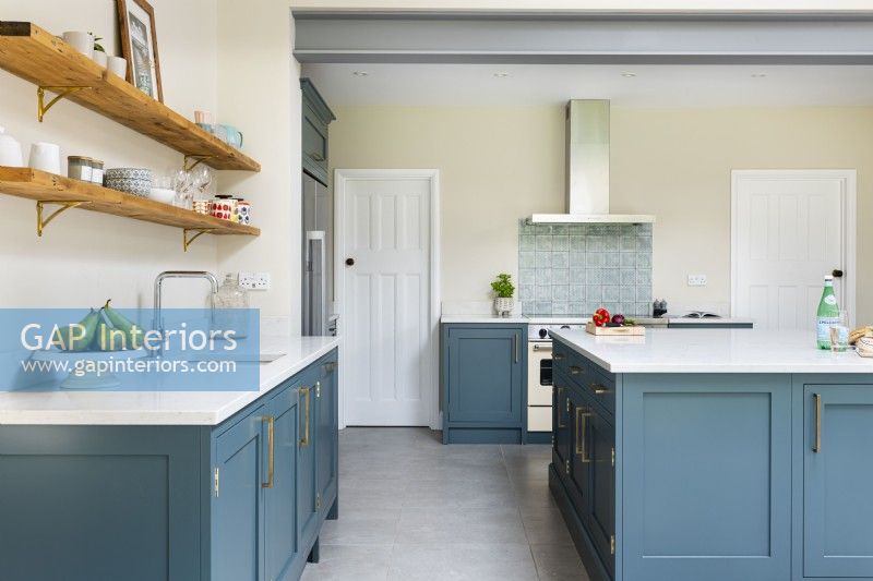 Modern classic kitchen with blue cupboards, island, open shelves, concrete floor tiles and exposed steel beam.