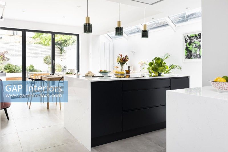 Modern classic kitchen with black island and courtyard beyond