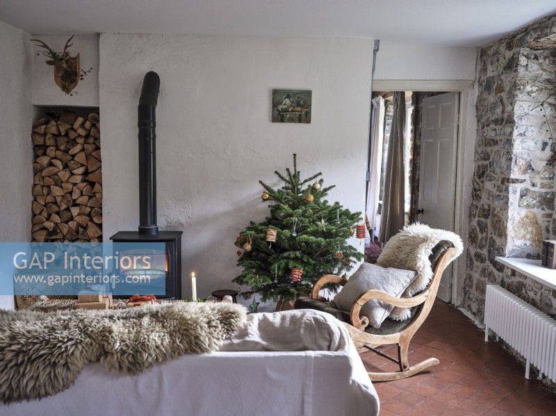Country living room featuring seating, a Christmas tree and a wood burning stove