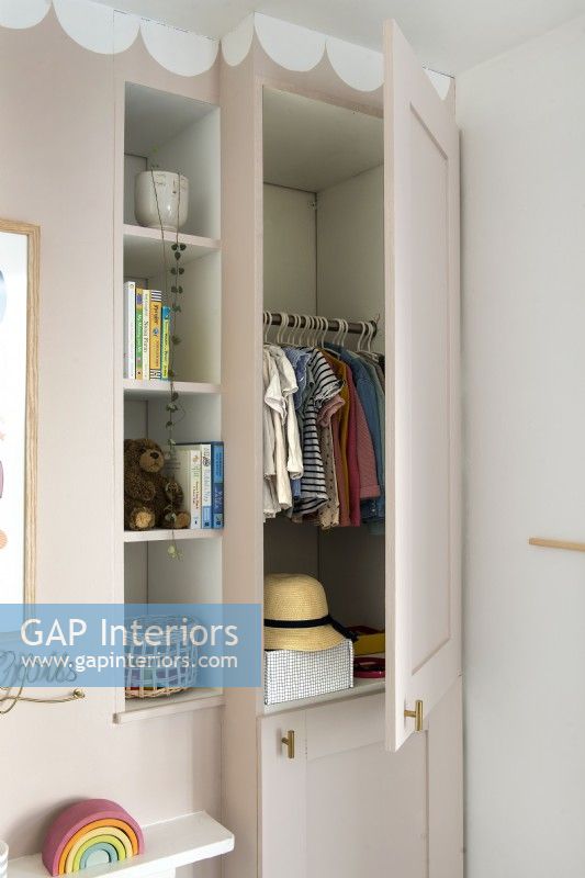 View of clothes in open wardrobe in childrens room