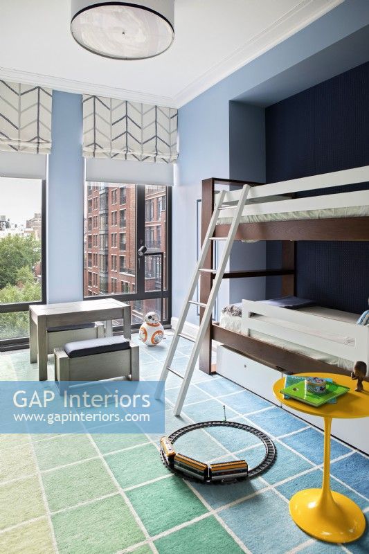 Boys blue bedroom with bunk beds and large windows with city view.