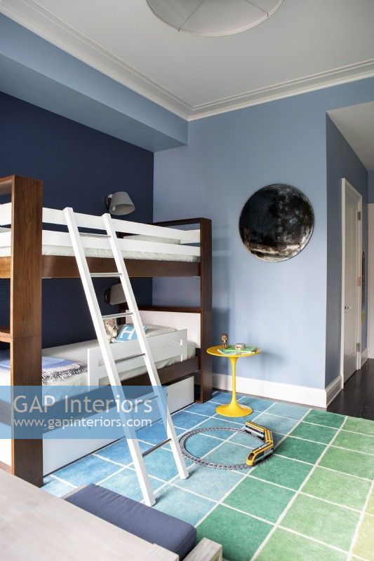 Boys blue bedroom with bunk beds and colourful square patterned rug.