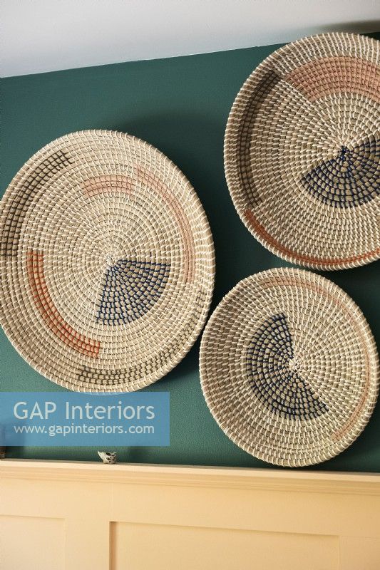 Display of woven plates on green bedroom wall - detail 