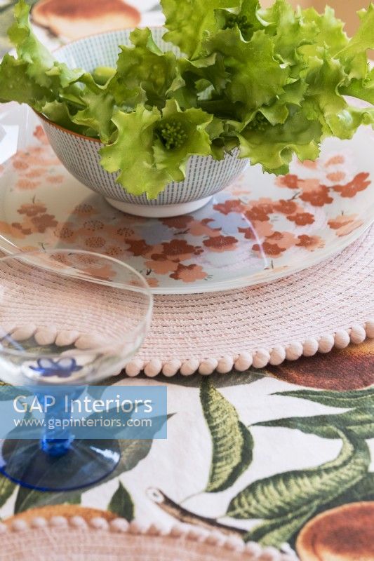 Detail of salad bowl, vintage plate and patterned tablecloth