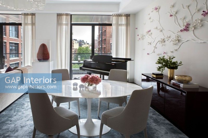 Dining table, chairs and piano in open plan living space with city view.