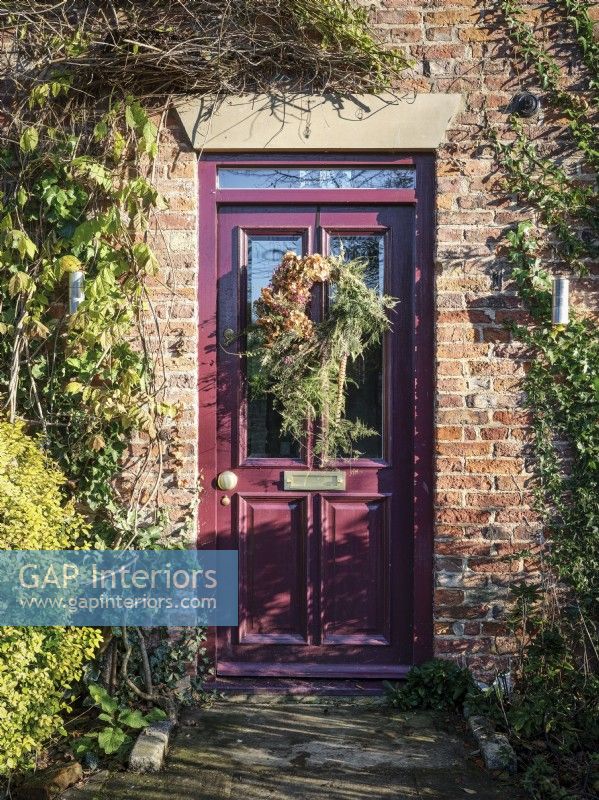 Front door of rustic cottage featuring Christmas wreath