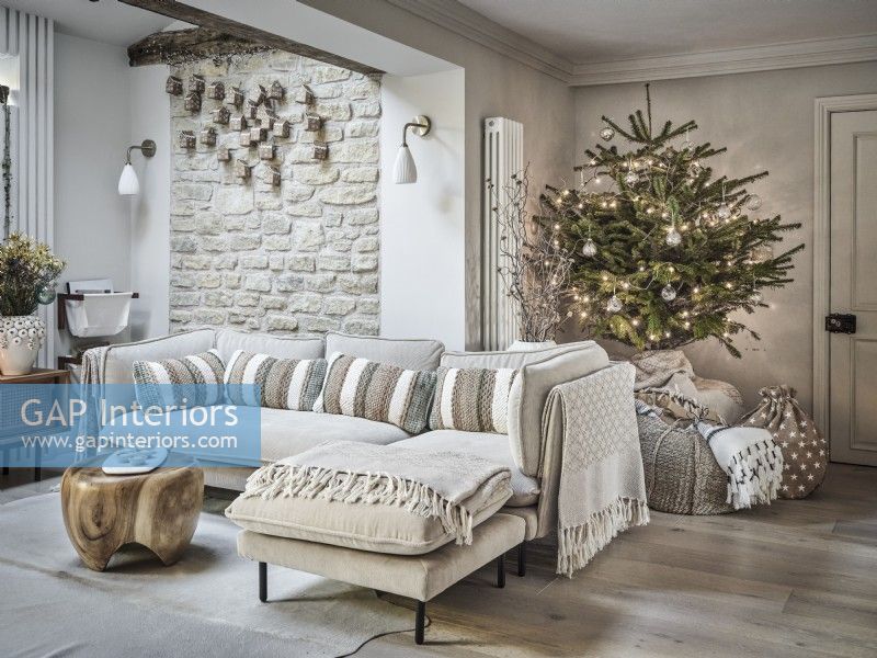 Seating area in neutral tones featuring Christmas tree and gifts