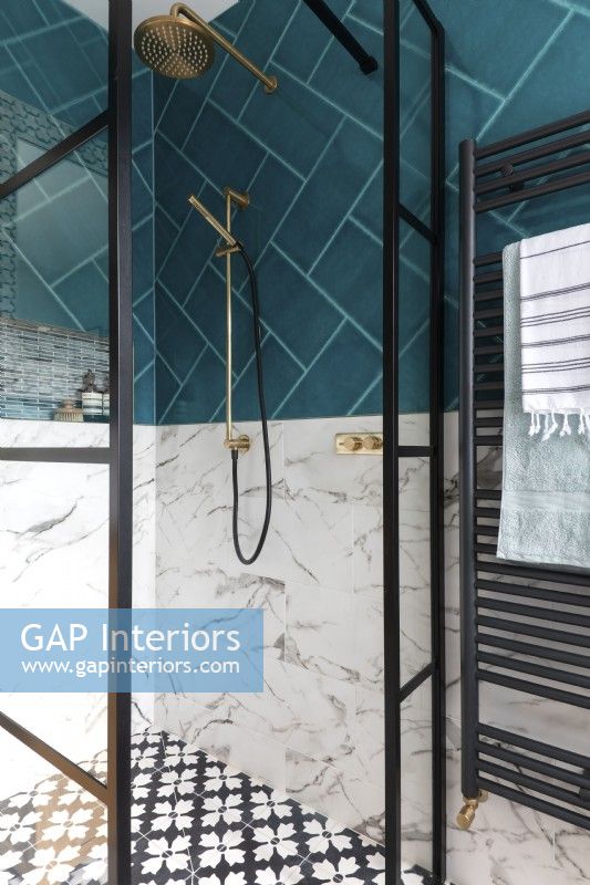 Shower enclosure with crittall style doors, brass shower head, marble tiles and teal tiles