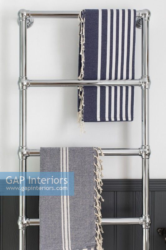Detail of chrome towel radiator, grey panelling and hamman towels