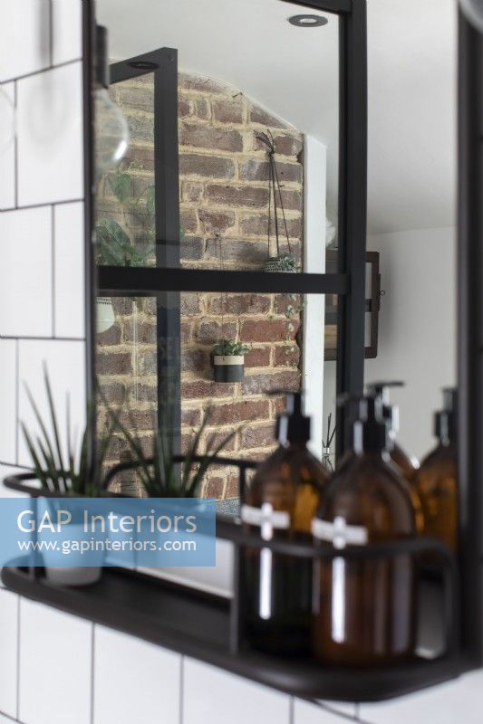 Reflection in mirror of exposed brick chimney breast and house plants
