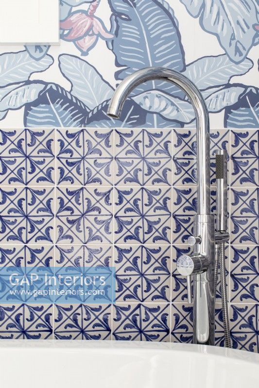 Detail of modern chrome bathroom taps for freestanding bath. Feature wallpaper

