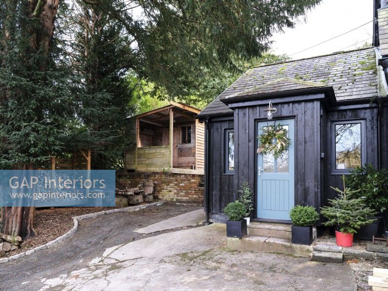 Country cabin with blue door and black timber cladding
