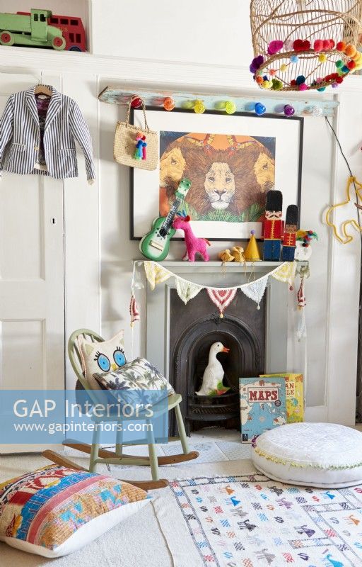 Fireplace in a Childs bedroom with display of vintage and bright coloured toys and decorations .