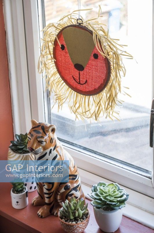 Lion and tiger ornaments on windowsill with small succulent plants
