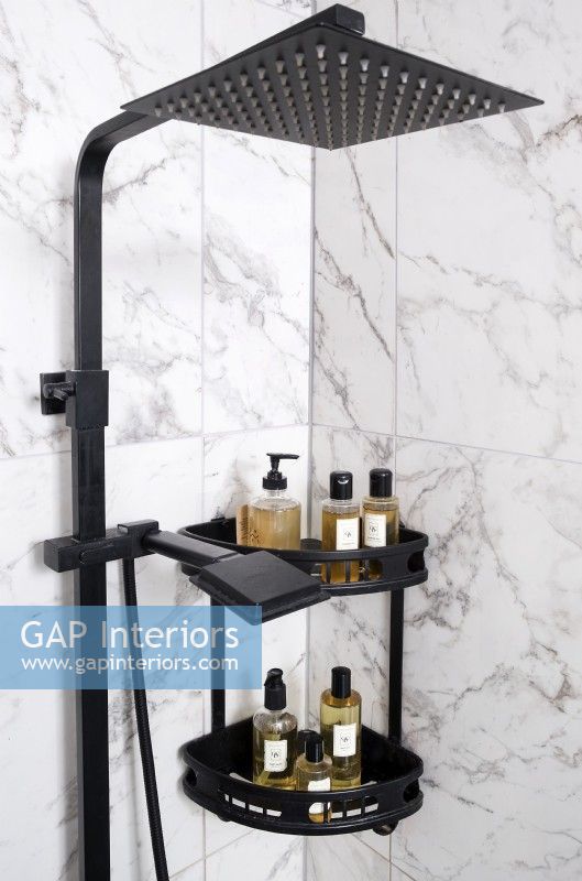 Detail of black shower head and shelving on marble tiled wall