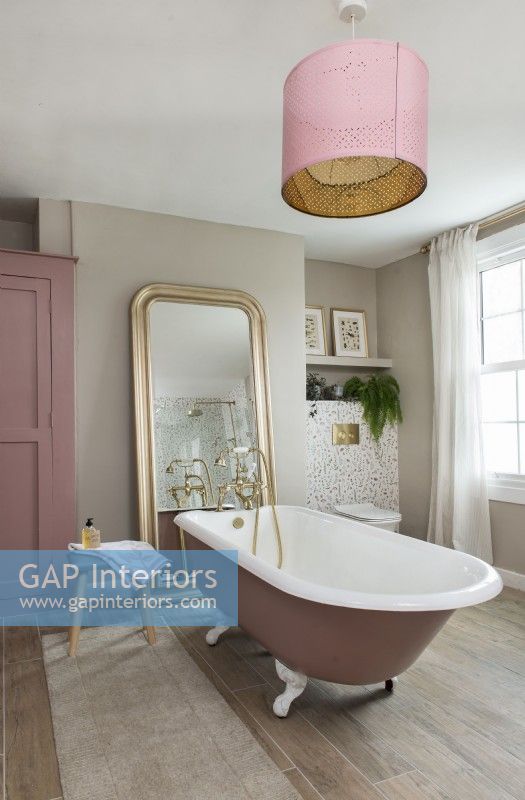 Feminine bathroom with pink rolltop bath
