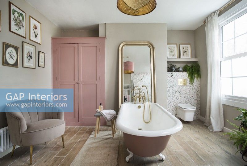 Vintage style feminine bathroom with pink rolltop bath and wardrobe