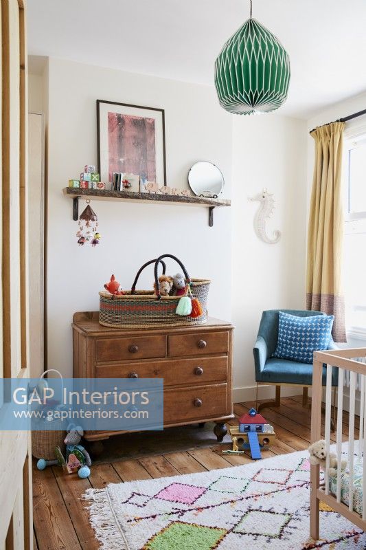 Childs bedroom nursery. Chest of drawers, pendant light, rug curtains and stripped pine floorboards 
