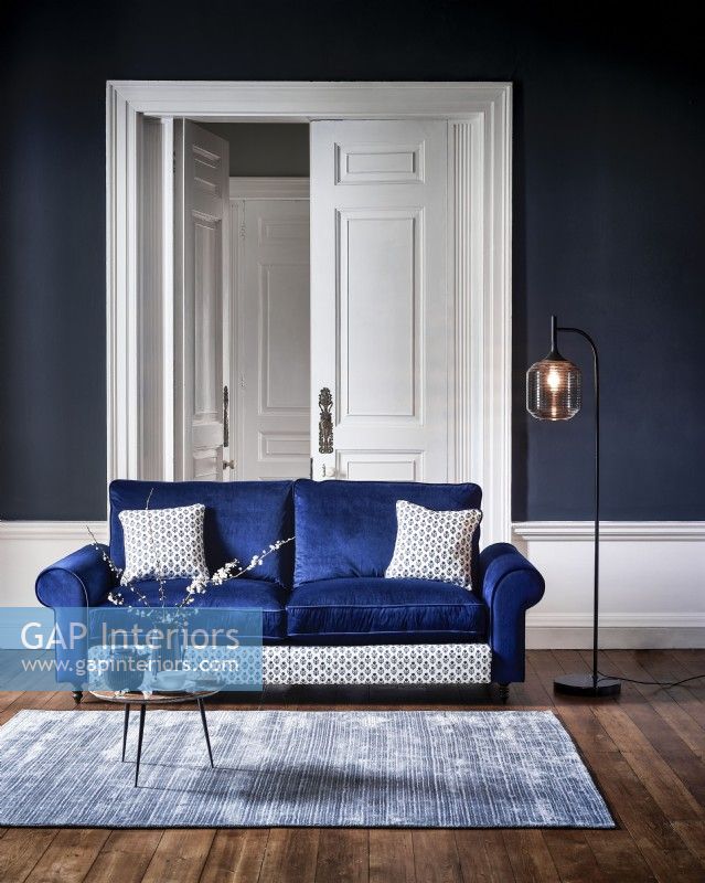 Modern blue sofa in a blue room with rug and lamp