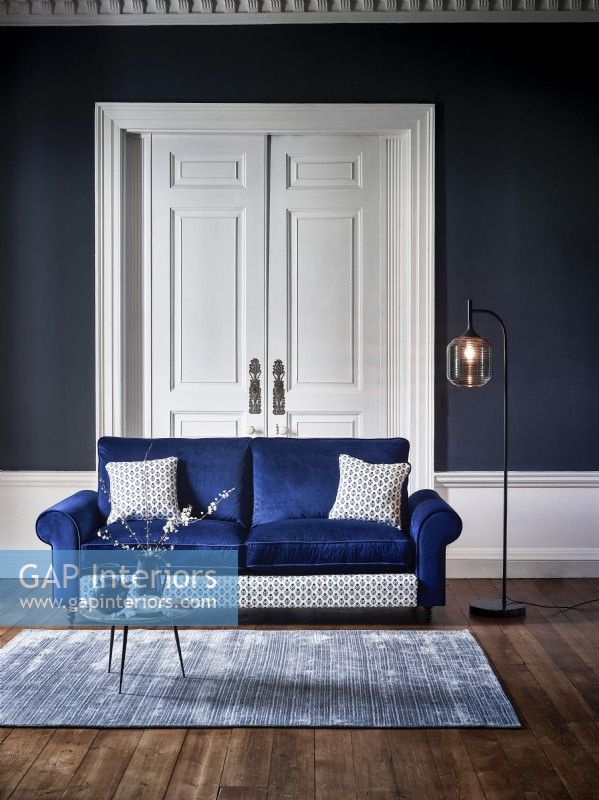 Modern blue sofa in a blue room with rug and floor lamp