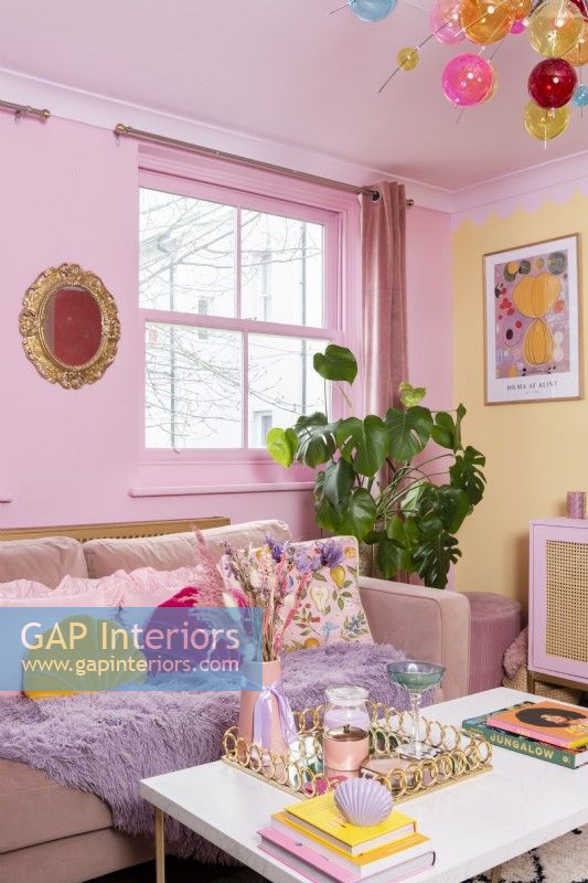 Corner of colourful living room with pink sofa and coffee table
