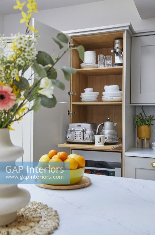 Modern kitchen with grey shaker-style cabinets. Hidden appliances in cupboard.