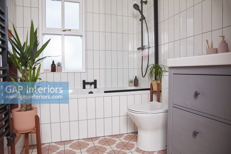Bathroom with colourful vinyl flooring, black fittings, white tiles and a grey under sink cupboard.