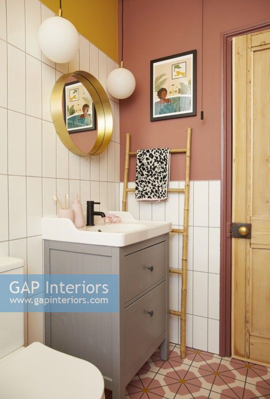 Bathroom with colourful vinyl flooring, white tiles and yellow and pink painted walls.