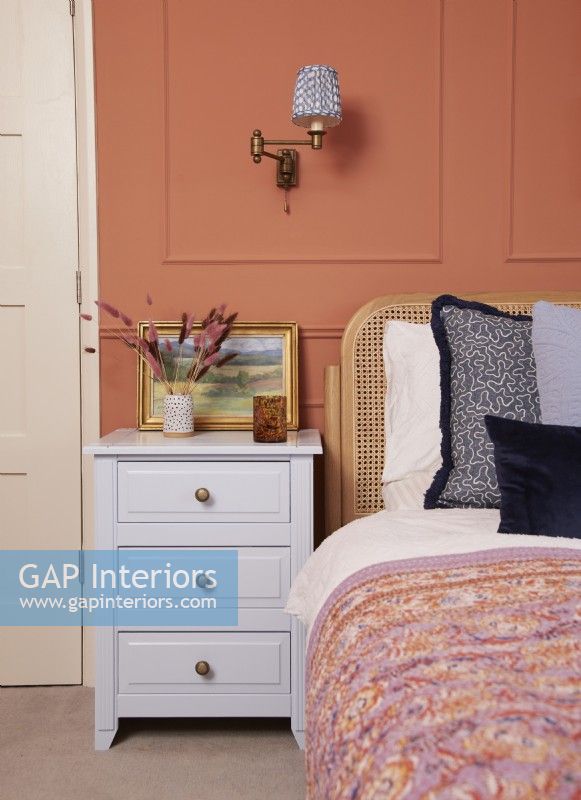 Bedroom detail with terracotta panelling and painted bedside cabinets.