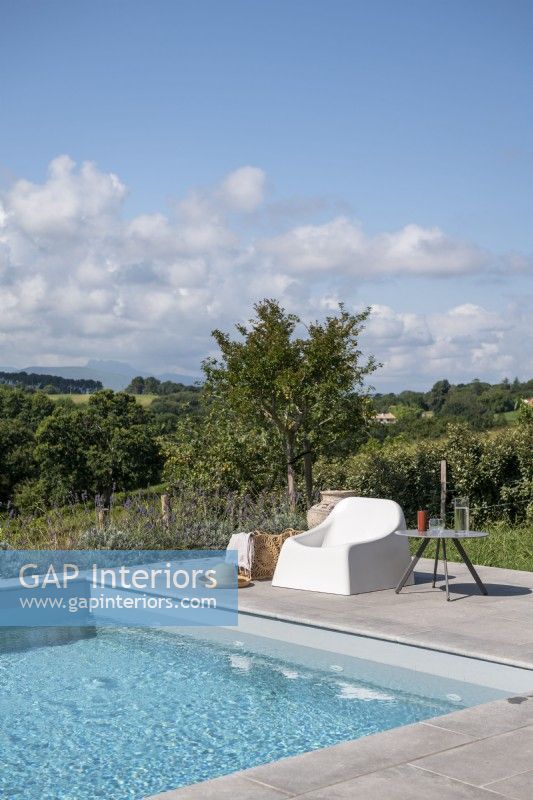 Modern chair next to outdoor swimming pool with countryside views