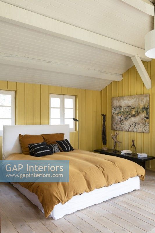 Modern country bedroom with yellow painted wooden walls