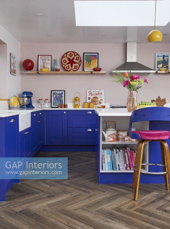 Colourful kitchen with cobalt blue cabinets, a breakfast bar and wooden flooring.