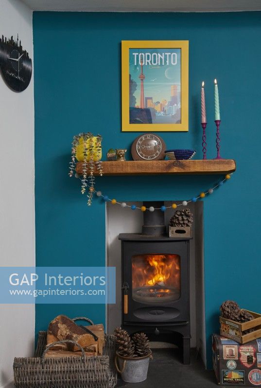 Living room detail of wood burner stove with teal blue painted wall.