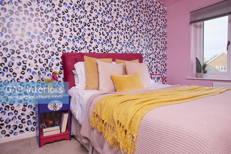 Colourful bedroom with animal print wallpaper and a pink painted wall.