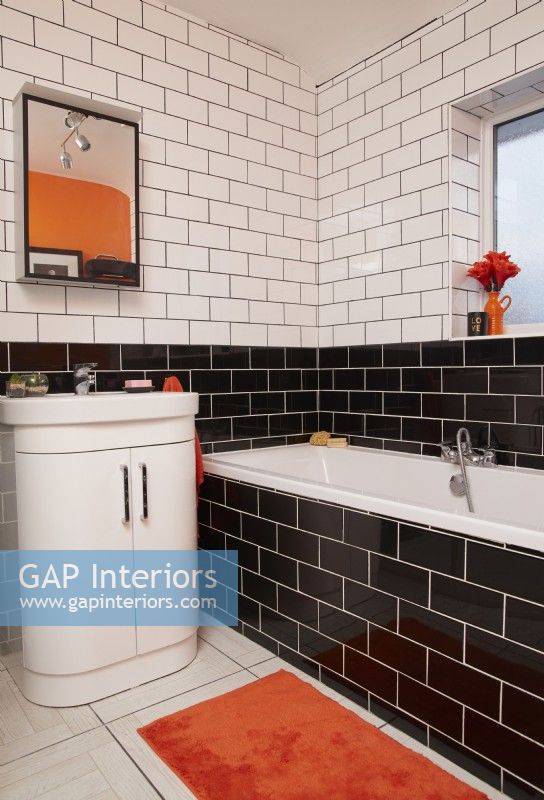 Bathroom with black and white metro tiles and orange accessories.