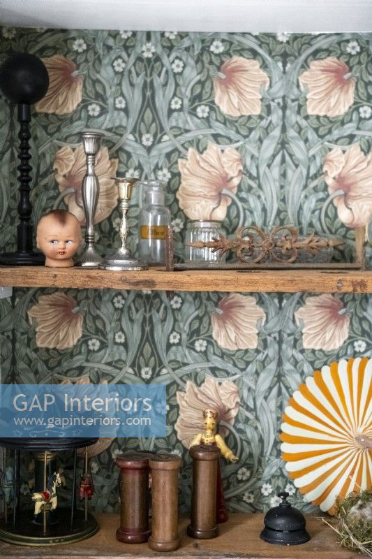 Detail of ornaments on shelves with patterned wallpaper backing